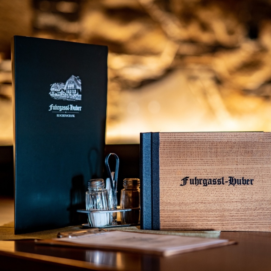 Zwei Restaurantkarten, Salz- und Pfefferstreuer und Utensilien auf einem Tisch mit unscharfem Hintergrund.